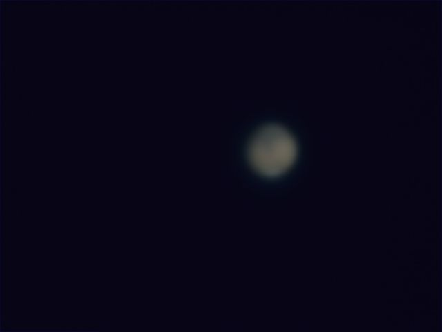 A fairly low-res shot of Mars, but note some darker regions and a bit of the southern polar region are visible.